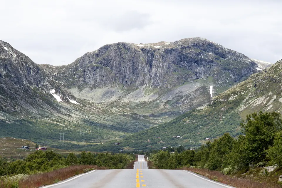Riksvei 52 mot bratte fjell og spredte hytter i Hemsedal en overskyet sommerdag