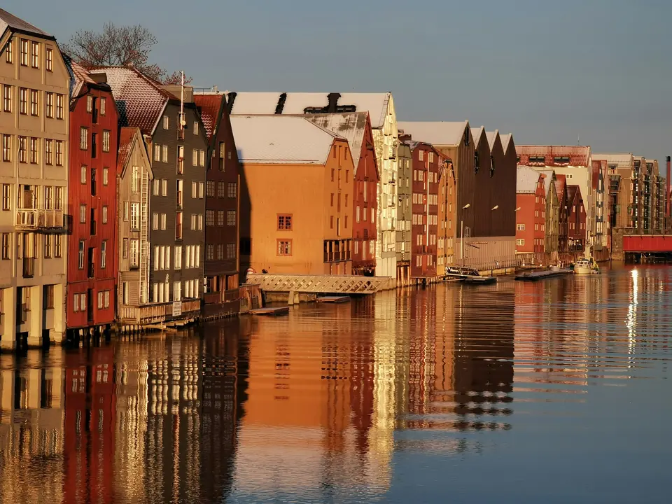 Fargerike bryggerekker langs Nidelva i Trondheim speiler seg i vannet i kveldssol